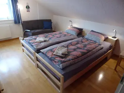 a bedroom with a large bed and a chair at 22 – Zimmer & Zmorge in Kreuzlingen