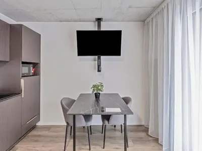 a dining room with a table with chairs and a tv at MOOI Apartments St.Gallen in St. Gallen