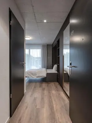 a room with a bedroom with a bed and a mirror at MOOI Apartments St.Gallen in St. Gallen