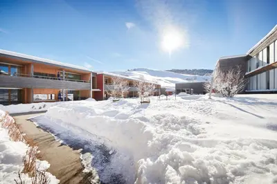 a snow covered yard in front of a building at Reka-Feriendorf Urnäsch in Urnäsch
