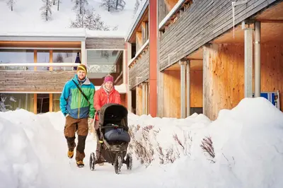 a man and woman walking through snow with a stroller at Reka-Feriendorf Urnäsch in Urnäsch