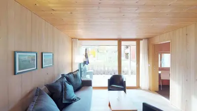 a living room with a couch and a large window at Reka-Feriendorf Urnäsch in Urnäsch