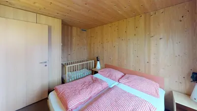 a bedroom with a bed in a wooden wall at Reka-Feriendorf Urnäsch in Urnäsch