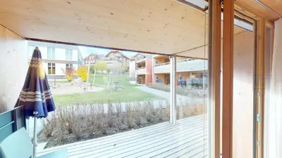 an open glass door to a deck with an umbrella at Reka-Feriendorf Urnäsch in Urnäsch