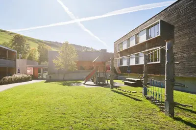 a building with a grass yard next to a building at Reka-Feriendorf Urnäsch in Urnäsch