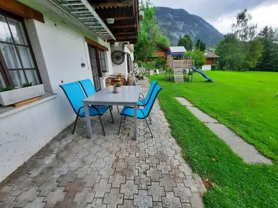 a table and chairs on a patio with a yard at Ferienwohnung Schafbergblick in Wildhaus