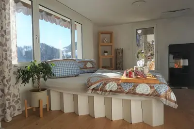 a bedroom with a large bed with a large window at HERZLI-CHALET über dem Rheintal mit Schlossblick in Werdenberg