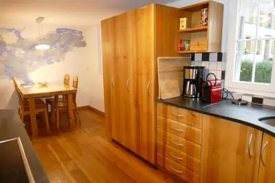 a kitchen with wooden cabinets and a small table at Family Landhaus Birwinken in Berg