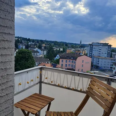a wooden bench sitting on a balcony with a city at Sonniges 1-Zimmerappartement mit Blick über Kreuzlingen in Kreuzlingen
