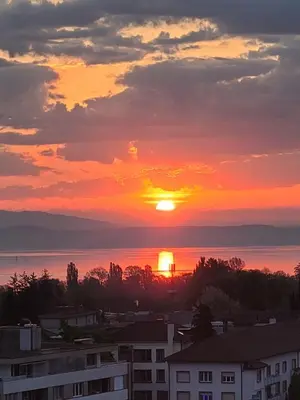 a sunset over a city with the sun setting at Lake View See & Bergsicht free parking in Kreuzlingen