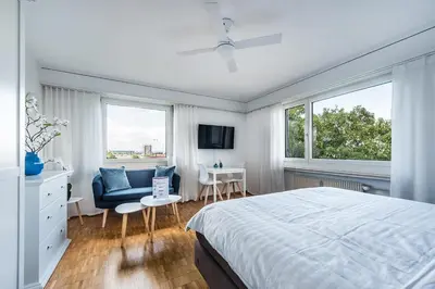 a bedroom with a bed and a chair and windows at SOHO 6 !Gratis Parken, Free Parking! in Kreuzlingen