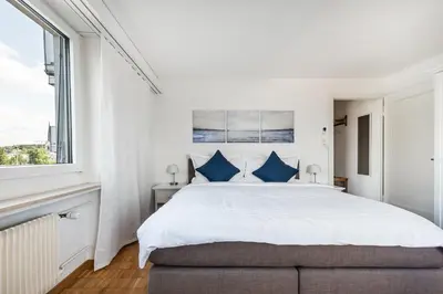 a white bedroom with a large bed with blue pillows at SOHO 6 !Gratis Parken, Free Parking! in Kreuzlingen