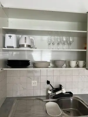 a kitchen with a sink and glasses on a shelf at Black&White Apartment in Uzwil