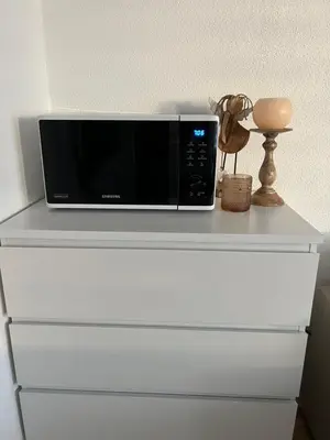 a microwave sitting on top of a white dresser at Black&White Apartment in Uzwil