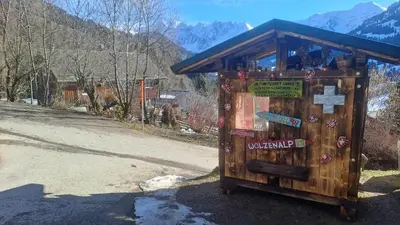 a wooden kiosk with signs on the side of a road at IB Säntis Chalet Chnorz Entire House in Nesslau
