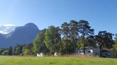a house in a field with mountains in the background at Treffpunkt Heuwiese in Weite
