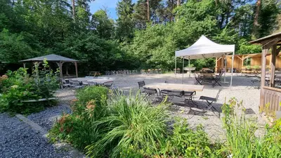 a patio with tables and chairs and a white umbrella at Treffpunkt Heuwiese in Weite