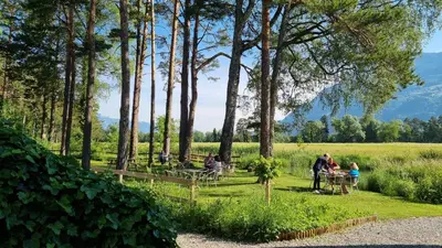 a group of people sitting at tables in a park at Treffpunkt Heuwiese in Weite