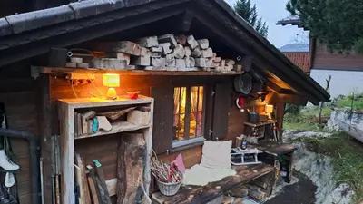 a small house with a pile of wood on the side at IB Säntis Chalet Chnorz Apartment in Nesslau