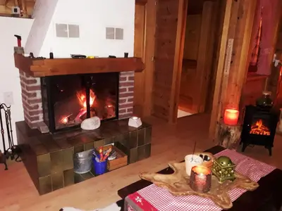 a living room with a fireplace and a table at IB Säntis Chalet Chnorz Apartment in Nesslau