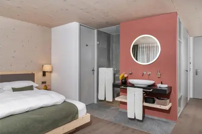 a bedroom with a bed and a sink and a mirror at Dorfhus Gupf in Rehetobel