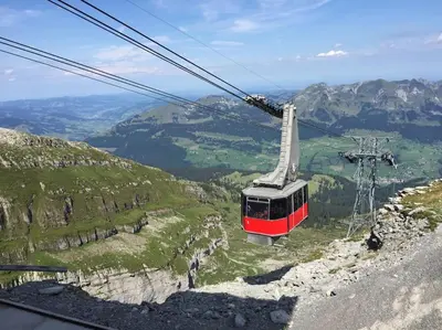 a red and white cable car on top of a mountain at Dachwohnung Zentrum Unterwasser in Unterwasser