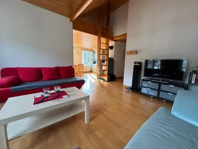a living room with a red couch and a table at Dachwohnung Zentrum Unterwasser in Unterwasser