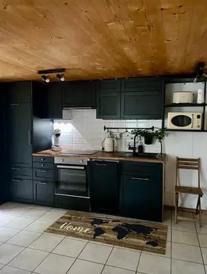 a kitchen with dark green cabinets and a table at Ferienwohnung in Stein AR in Stein