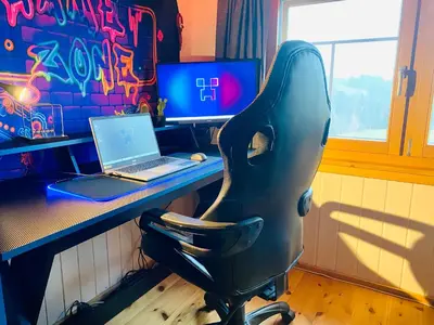 a desk with a laptop computer and a black chair at Birkenhof, Haus Märli in Herisau