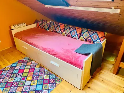 a small bed in a room with a colorful rug at Birkenhof, Haus Schwänli in Herisau