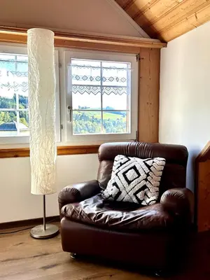 a brown leather chair in a room with a window at Wunderschöne Maisonette-Ferienwohnung in stattlichem Toggenburgerhaus in Sankt Peterzell
