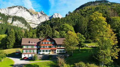 a large house in the mountains with trees at Ferienheim Bodenweidli in Wildhaus