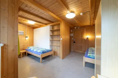 a room with two beds in a room with wooden walls at Ferienheim Bodenweidli in Wildhaus