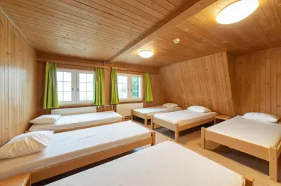 a room with four beds in a wooden room at Ferienheim Bodenweidli in Wildhaus