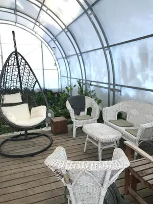 a patio with chairs and a swing in a greenhouse at Bijou 1 Hübsche 1 Zimmer Wohnung in Herisau