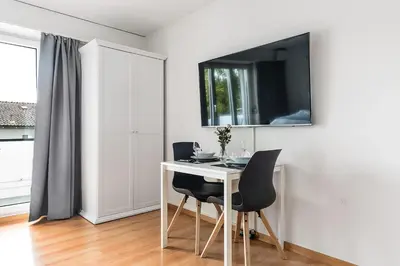 a white table with two chairs and a television on a wall at SOHO 3B !Gratis Parken, Free Parking! in Kreuzlingen