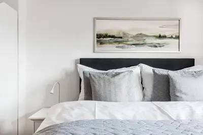 a white bedroom with a bed with white sheets and pillows at SOHO 3B !Gratis Parken, Free Parking! in Kreuzlingen