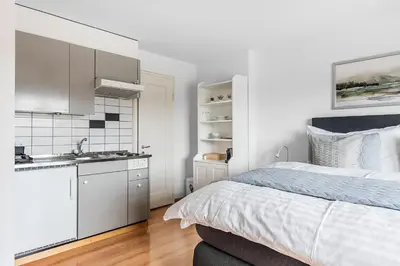 a white bedroom with a bed and a kitchen at SOHO 3B !Gratis Parken, Free Parking! in Kreuzlingen