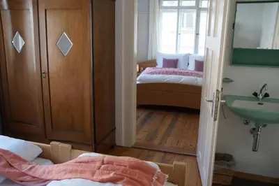 a bathroom with a sink and a bedroom with two beds at Villa Donkey BnB in Degersheim
