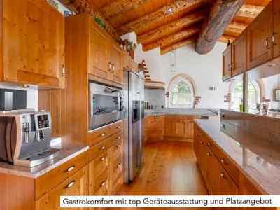 a large kitchen with wooden cabinets and stainless steel appliances at Chalet Müsli in Wildhaus