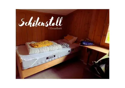 a small bed in a wooden room at Chalet Müsli in Wildhaus