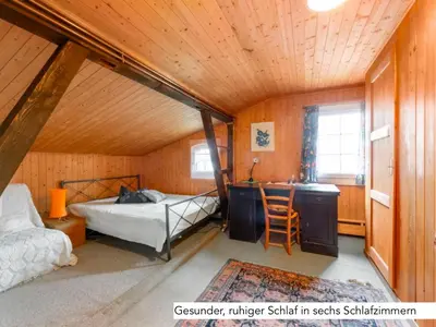 a bedroom with a bed and a desk in a room at Chalet Müsli in Wildhaus