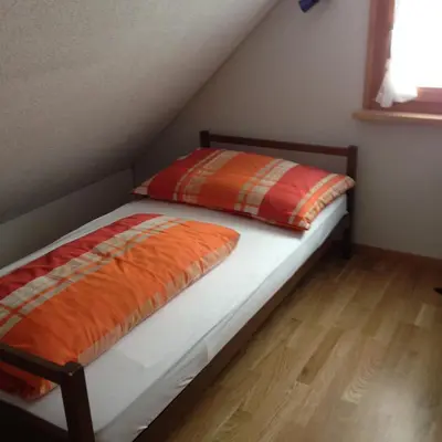 a bed with orange and orange pillows in a room at Ferienhaus Rütiweid in Appenzell