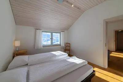 a bedroom with a white bed and a window at Undereggli in Nesslau