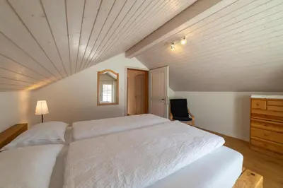 a bedroom with a large white bed with a wooden ceiling at Undereggli in Nesslau