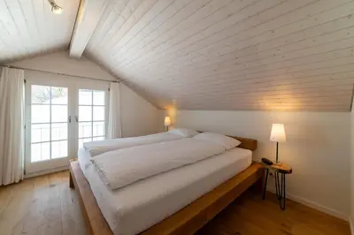 a bedroom with a large bed and a large window at Undereggli in Nesslau