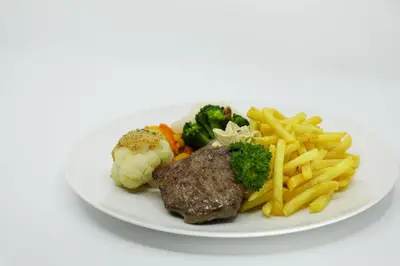a plate of food with meat and french fries at Hotel und Gasthaus Bad Gonten in Gonten