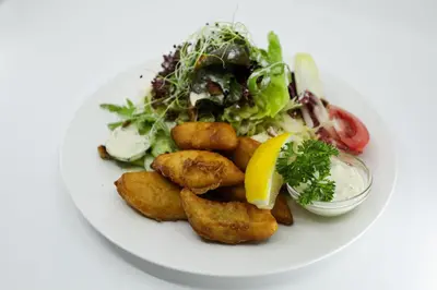 a plate of food with a salad and a lemon wedge at Hotel und Gasthaus Bad Gonten in Gonten