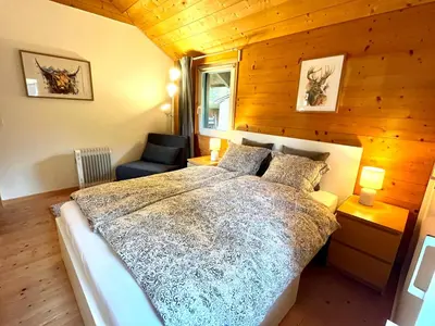 a bedroom with a large bed and a chair at Chalet - Kleines Paradies - in Appenzell