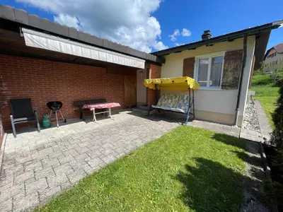 a patio of a house with a table and a grill at Stockberghüsli in Nesslau
